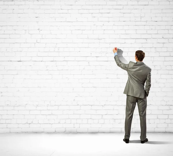 Businessman drawing sketches on wall — Stock Photo, Image