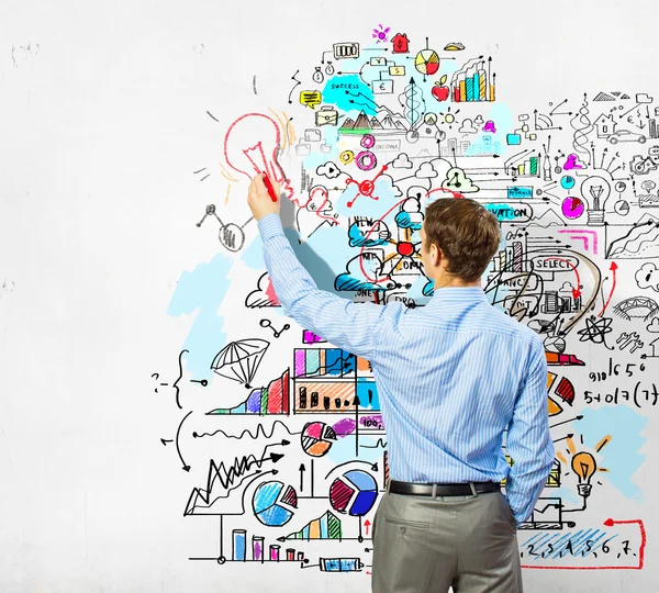 Businessman drawing sketches on wall — Stock Photo, Image