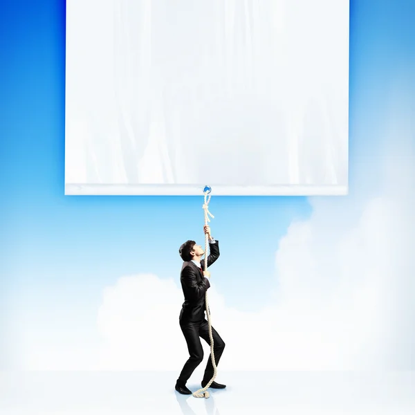Businessman pulling blank banner — Stock Photo, Image