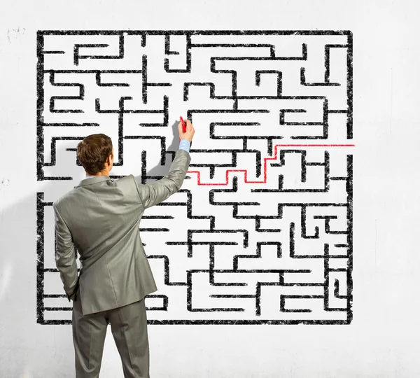 Businessman solving labyrinth problem — Stock Photo, Image