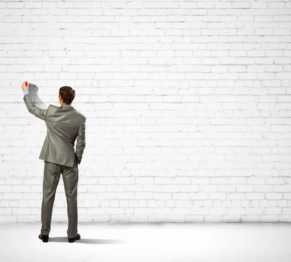 Businessman drawing sketches on wall — Stock Photo, Image