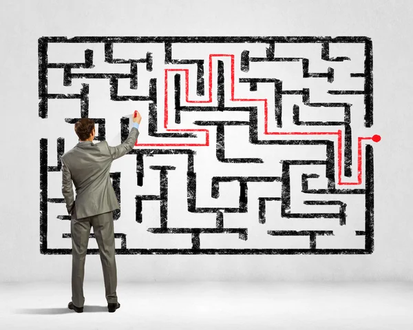 Businessman solving labyrinth problem — Stock Photo, Image