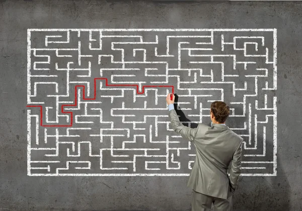Businessman solving labyrinth problem — Stock Photo, Image