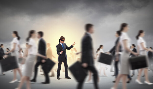 Businessman in blindfold among group of people