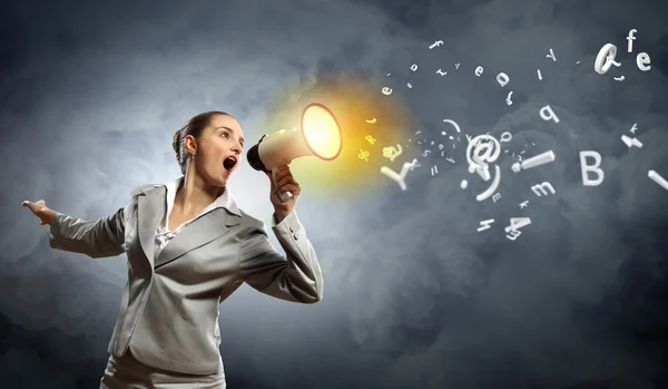 Businesswoman in grey suit screaming into megaphone — Stock Photo, Image