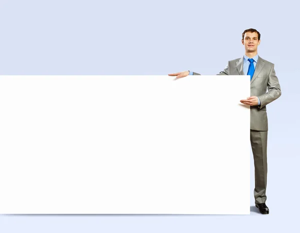 Empresario sosteniendo banner en blanco — Foto de Stock