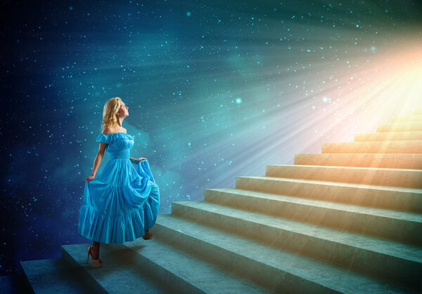 Young woman in blue dress walking up the stairs