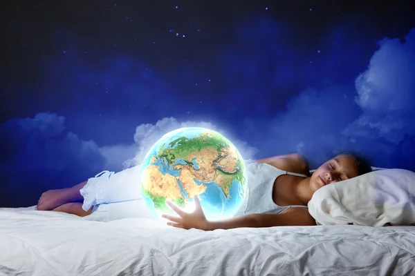 Девушка спит в постели и смотрит на планету Земля — стоковое фото
