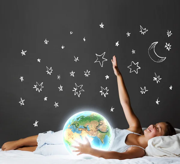 Menina dormindo na cama e olhando para o planeta Terra — Fotografia de Stock