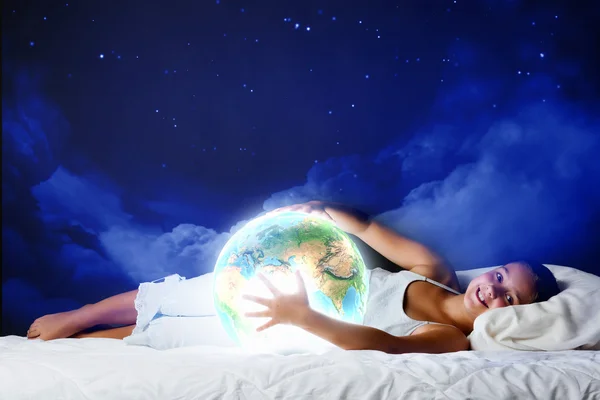 Mädchen schläft im Bett und schaut auf den Planeten Erde — Stockfoto