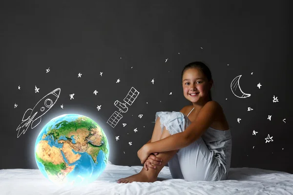 Girl sitting in bed and looking at Earth planet — Stock Photo, Image