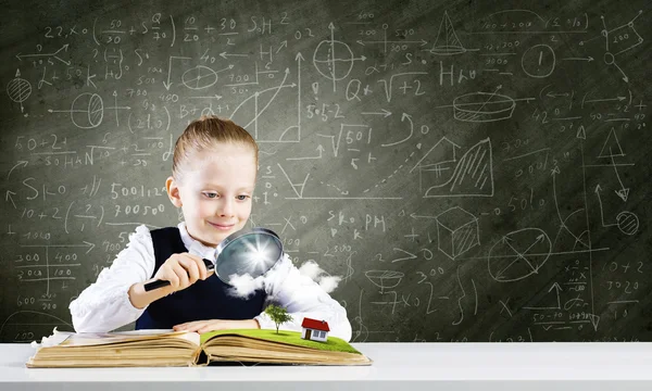 Schoolmeisje onderzoeken geopend boek — Stockfoto