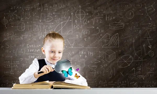 Schoolgirl examining opened book — Stock Photo, Image