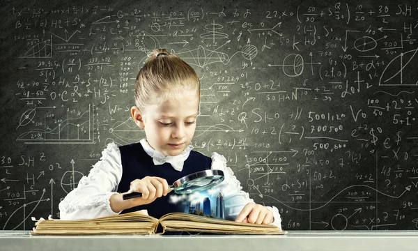 Schoolmeisje onderzoeken geopend boek — Stockfoto