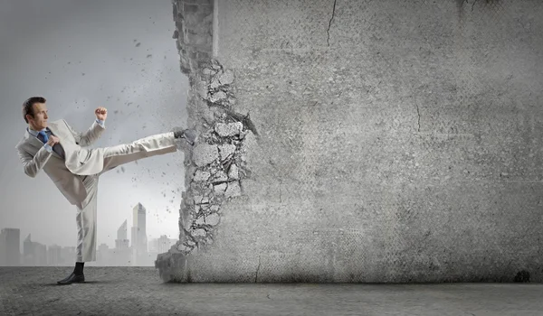 Businessman breaking stone wall — Stock Photo, Image