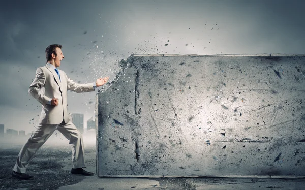 Businessman breaking stone wall — Stock Photo, Image