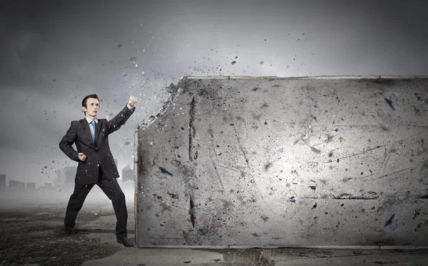 Businessman breaking stone wall — Stock Photo, Image