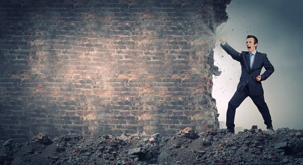 Businessman breaking stone wall — Stock Photo, Image