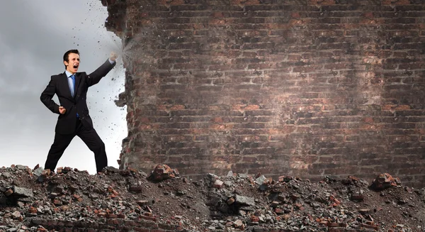 Businessman breaking stone wall — Stock Photo, Image