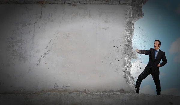 Businessman breaking stone wall — Stock Photo, Image