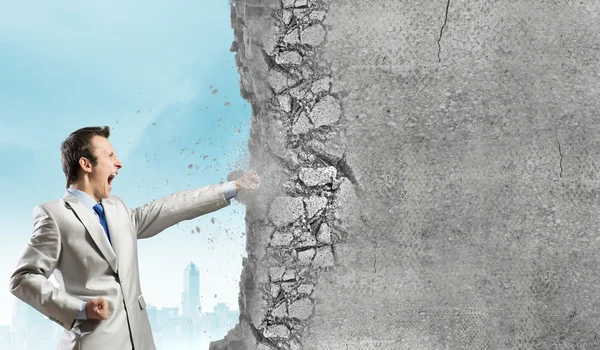 Businessman breaking stone wall — Stock Photo, Image