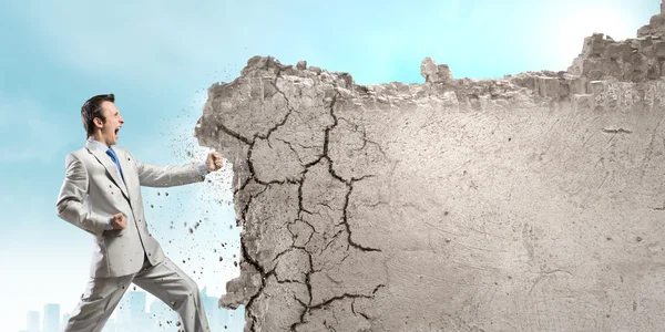 Businessman breaking stone wall — Stock Photo, Image