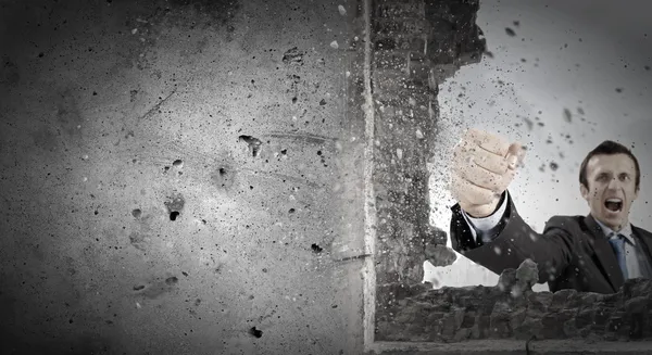 Businessman breaking stone wall — Stock Photo, Image