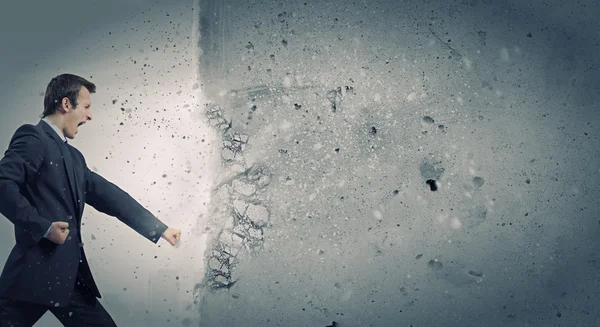 Businessman breaking stone wall — Stock Photo, Image