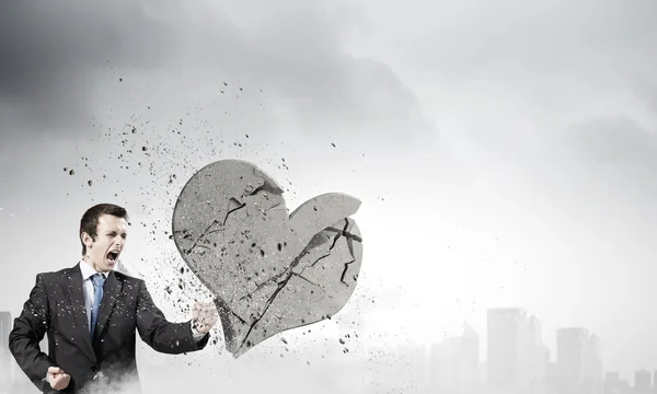 Businessman breaking stone heart