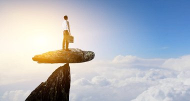 Dağın tepesinde duran takım elbiseli genç adamın arka manzarası. - Evet. Karışık ortam