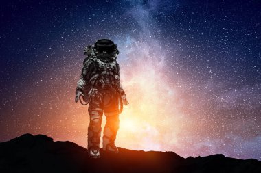 Keşfedilmemiş bir gezegende yürüyen astronot. Karışık ortam