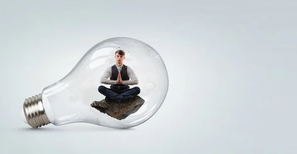 Бізнесмен робить йогу в позі лотоса всередині лампочки — стокове фото