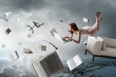 Genç bir kadın kitap okurken havada duruyor.