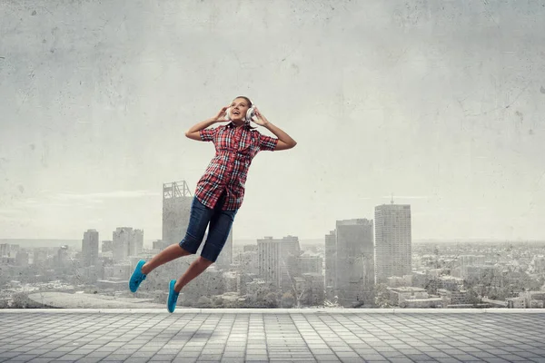 Een vrouw met koptelefoon die springt. Gemengde media — Stockfoto