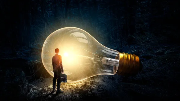 Huge light bulb glowing in the darkness . Mixed media — Stock Photo, Image