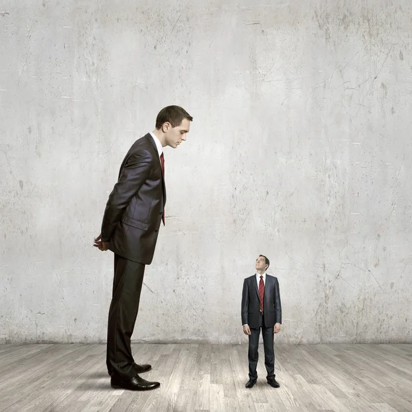 Businessman looking down at small businessman — Stock Photo, Image