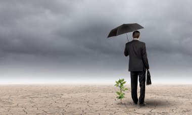 şemsiye ile küçük Fideler koruyan işadamı