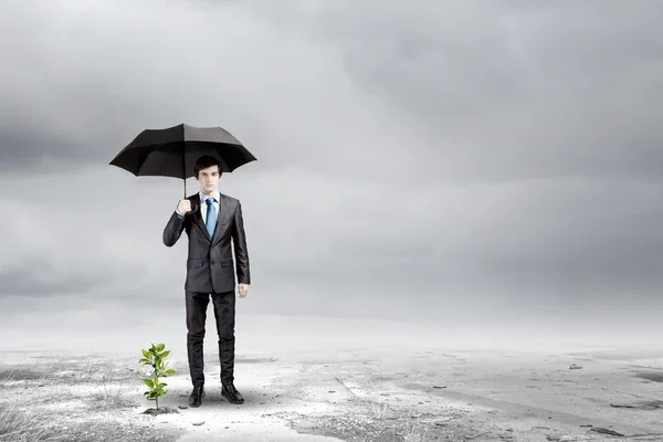 Affärsman skydda spira med paraply — Stockfoto