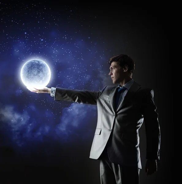 Affärsman håller månen planet — Stockfoto