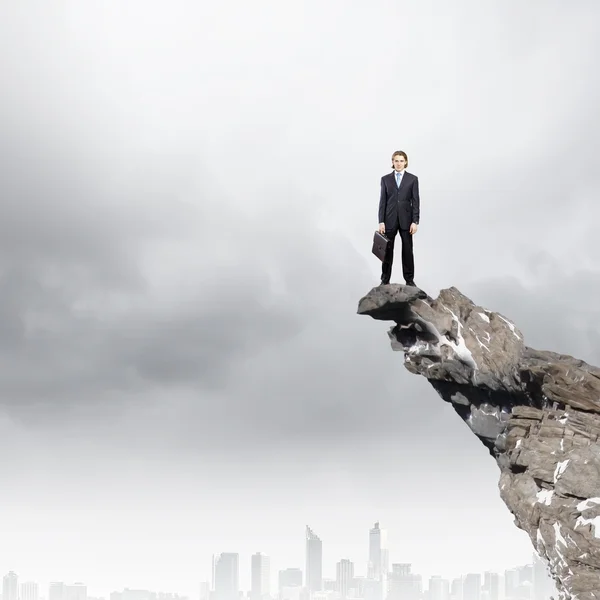 Businessman standing on edge of rock — Stock Photo, Image