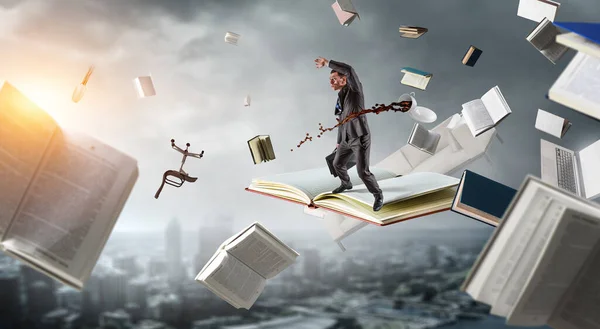 Biznesmen balansujący na szczycie latającej książki. Media mieszane — Zdjęcie stockowe