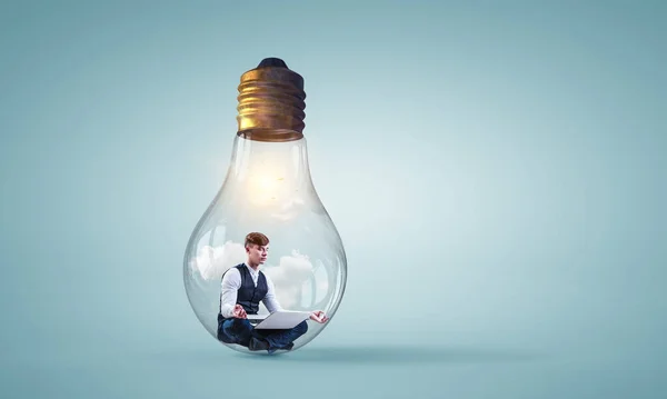 Бізнесмен робить йогу в позі лотоса всередині лампочки — стокове фото