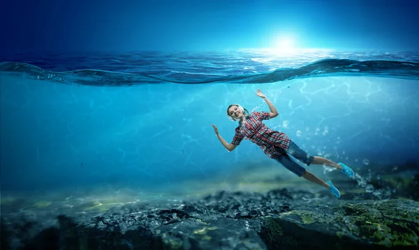 Mujer con auriculares bajo el agua. Medios mixtos — Foto de Stock
