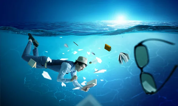 Een man die een boek onder water leest — Stockfoto