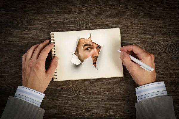 Man gezicht door het gat in papier — Stockfoto