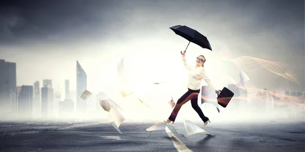 Businesswoman running with umbrella . Mixed media — Stock Photo, Image