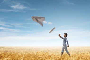 Mutlu çocuk kağıt uçakla oynuyor.