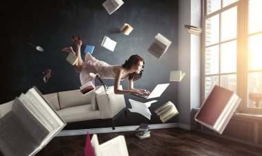 Genç bir kadın kitap okurken havada duruyor.