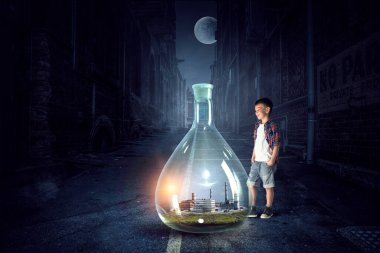 İçinde manzara olan cam matara tutan bir çocuk.