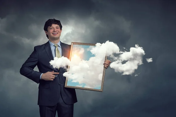 Homem segurando quadro com céu azul e nuvens. Meios mistos — Fotografia de Stock